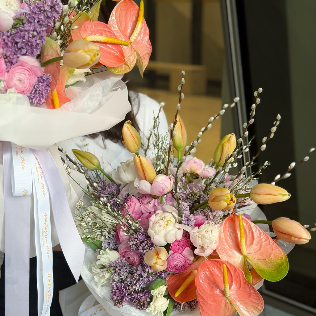 Bouquet of flowers with pink tulips, purple flowers, and red anthuriums.