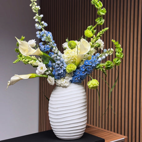 Calla lilies, delphinium and lisianthus flower arrangement in a modern vase in Miami