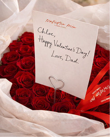 Bouquet of red roses with a card reading 'Happy Valentine's Day! Love, Dad.'