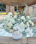 Bouquet of white flowers in a vase in front of a fountain