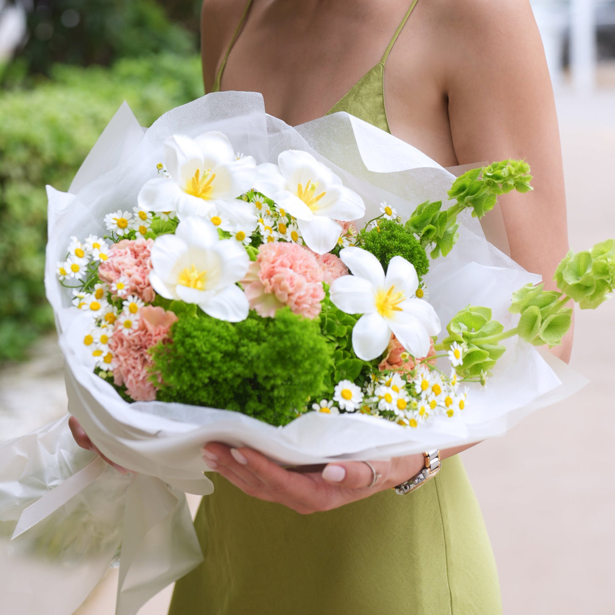 White tulips, pink carnations and chamomile bouquet held outdoors