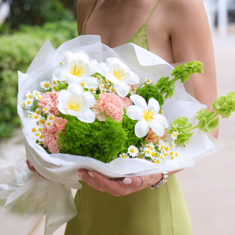 White tulips, pink carnations and chamomile bouquet held outdoors